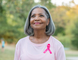A woman in a pink shirt with a breast cancer ribbon