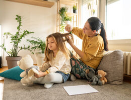 A mother runs a comb through a girl’s long hair.