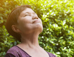 A woman tilts her head back as she breathes.