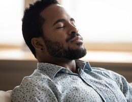 A man tilts his head back and closes his eyes.