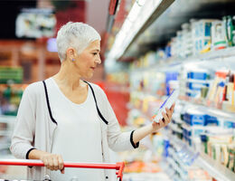 A woman shopping in the dairy aisle of a grocery store.