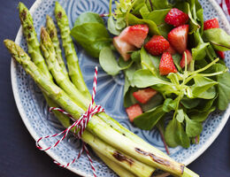 Asparagus, strawberries and spinach on a plate.